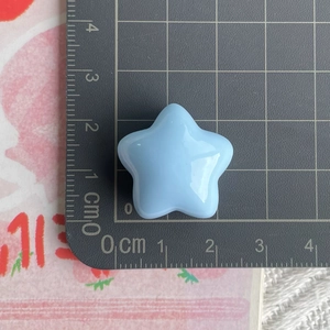 Macro shot of 2.5cm light blue star resin accessory on a metric measurement grid mat