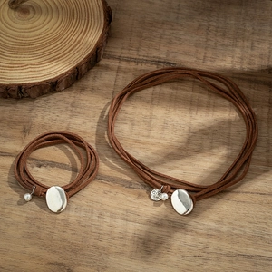 Double-layer brown leather cord choker with silver oval pendants and white pearls on wood