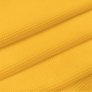 Detailed macro view of vibrant yellow waffle texture fabric on this men's polo shirt