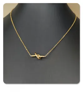 Detailed view of gold knot pendant necklace on a black mannequin bust minimalist design