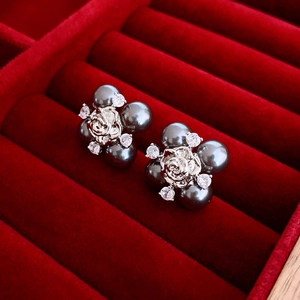 Boucles d'oreilles fleur vintage avec perles noires et zircons sur fond velours rouge