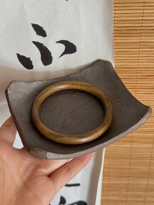 Gros plan d'un bracelet en bois poli avec veinage naturel sur une assiette en céramique
