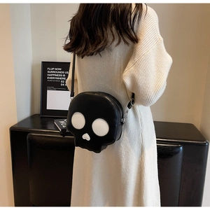 Detail of creative skull crossbody bag in black leather worn by a model in casual knitwear