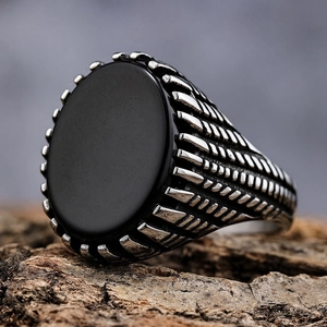 Men's vintage stainless steel ring with oval black onyx gemstone on wood surface