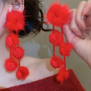 Detail of red plush pompom and rose long fringe earrings with elegant crystal beads