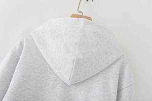 Detail of the hoodie's hood on a wooden hanger showing grey marl knit fabric texture