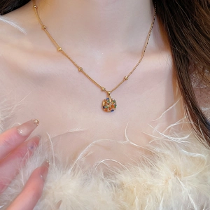 Close-up of gold plated necklace with a colorful circular gemstone pendant on a model