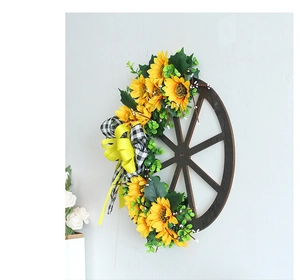 Detailed view of artificial sunflower wreath on dark wooden wheel with yellow plaid bow
