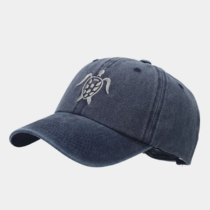 Detailed side view of dark blue washed denim baseball cap with grey turtle embroidery