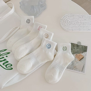 Detail of five white cotton socks with colorful embroidered smiley faces in five shades