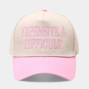 Close-up of pink embroidery reading EXPENSIVE & DIFFICULT on beige cotton baseball cap