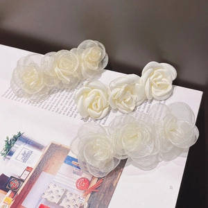 Detail of cream camellia hair clips in organza and satin textures on a magazine