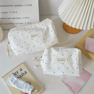 Detailset weißer Kosmetiktaschen mit blauem Herzmuster in einer gemütlichen Lifestyle-Umgebung