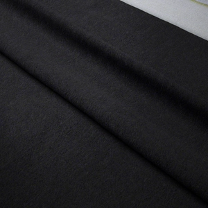 Macro detail of high-quality black bohemian tapestry fabric showing plush texture and thickness