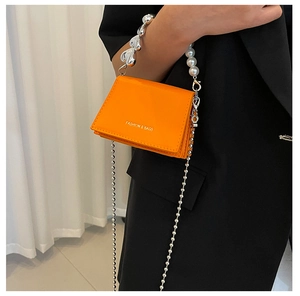 Detail of orange PU leather mini bag featuring decorative pearl and heart chain handle