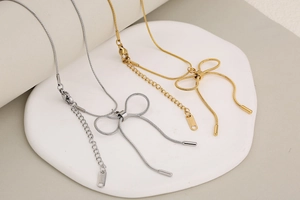 Detailed close-up of gold and silver bow necklaces with sleek snake chains and clasp