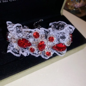 Détail de pierres rouges sur un bracelet en dentelle blanche dans un écrin noir