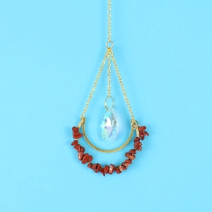 Detail of suncatcher pendant with gold chain, red stones and a crystal teardrop