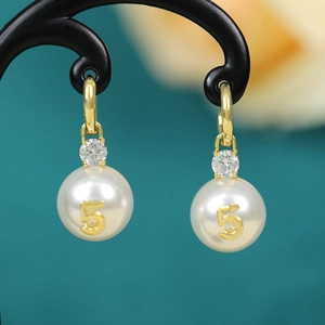 Detail of luxury pearl earrings with golden number five design and clear cubic zirconia stones