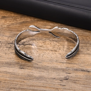 Macro detail of men's vintage stainless steel cuff bracelet with intricate feather pattern