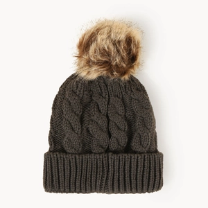 Detail of dark brown cable knit beanie featuring a fluffy faux fur pompom and ribbed cuff