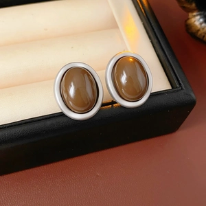 Close-up of vintage oval silver studs with polished brown gemstones in jewelry box