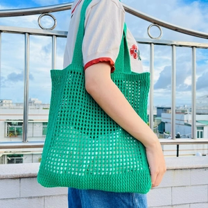 Detail shot of green knit mesh tote bag showing intricate woven hollow-out pattern