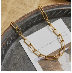 Macro detail of golden paperclip chain necklace on vintage newspaper and card