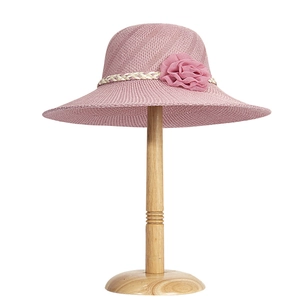 Detail view of pink woven straw sun hat with decorative fabric flower and ribbon trim
