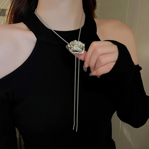 Detailed view of silver rose necklace with sparkling rhinestones on black knitwear