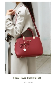 Red leather handbag featuring a stylish bow and gold star pendant on a beige trench coat