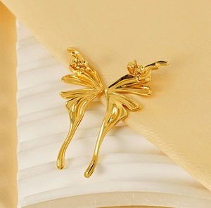 Macro shot of gold butterfly wing earrings with a polished finish on a white base