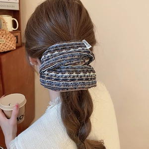 Détail d'un chouchou en tissu tricoté coloré avec étiquette tissée sur tresse de cheveux