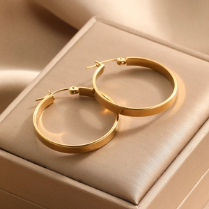 Minimalist gold hoop earrings with matte finish displayed on a luxury champagne jewelry box