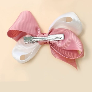 Détail d'un nœud en ruban gros-grain rose et blanc avec pince crocodile en métal au dos