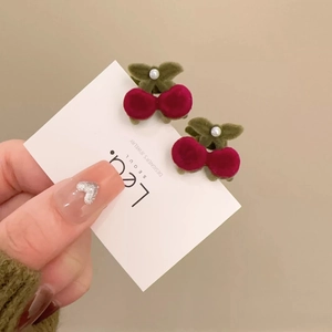 Detail of red flocked cherry hair clips with soft velvet texture and white pearls