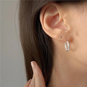 Textured silver hoop earrings with minimalist stud on ear model closeup view