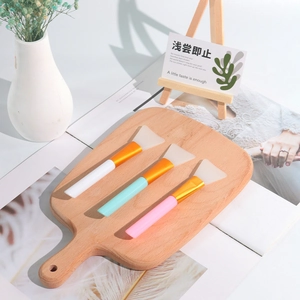 Set di 3 pennelli per maschera in silicone con manici colorati su tagliere di legno rustico