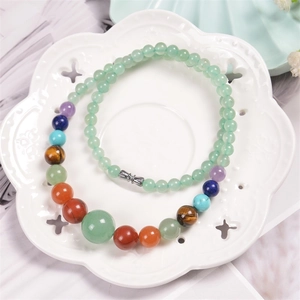 Detailed close-up of bohemian colorful natural stone beads on a ceramic floral tray