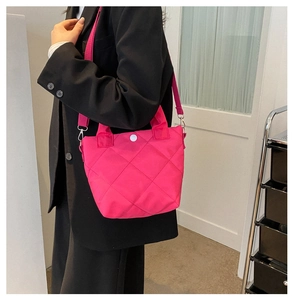 Close-up of quilted fuchsia handbag with white button closure and wide fabric strap