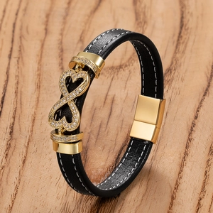 Close-up of black braided leather bracelet with golden infinity and heart charm