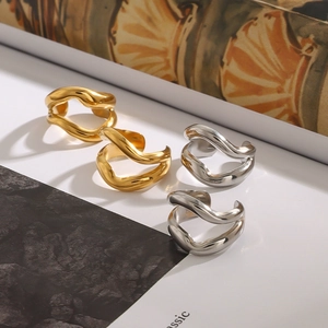 Set of four wavy open rings in polished gold and silver finishes on a stone background