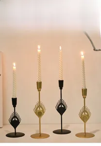 Close-up of golden and black metal candle holders with feather design and lit candles