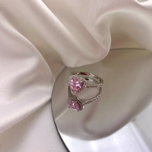 Macro d'une bague coeur rose en zircon avec diamants pavés sur fond de soie blanche élégante