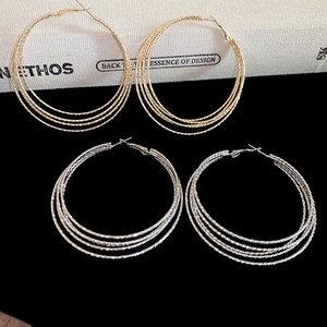 Detail of multi-layer round hoop earrings in gold and silver finish on black background