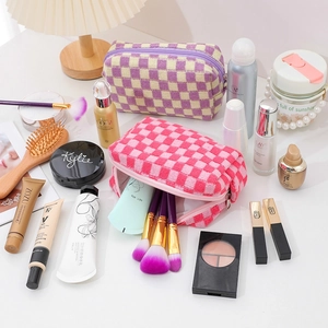 Flat lay of pink and purple checkered knit makeup bags with cosmetic accessories