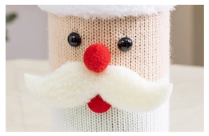 Macro della fodera per bottiglia a Babbo Natale in maglia con barba in peluche