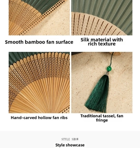 Close-up of dark green silk folding fan with intricate hand-carved bamboo frame details