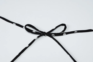 Detailed view of the black and white polka dot self-tie bow on a stylish summer dress