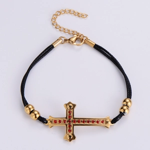 Golden cross bracelet with red stones on a black woven cord with adjustable chain